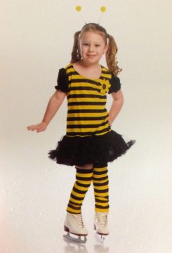 A young girl in a bee costume with yellow and black stripes, wearing ice skates.