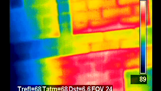 A thermal imaging scan displaying temperature gradients across a surface. Thermal camera view showing temperature variations with FLIR branding and data overlays