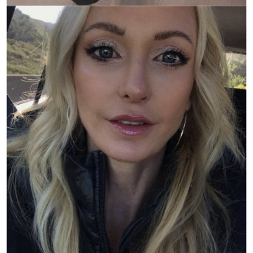 Screenshot of the Bumble app showing a profile with two photos: one of feet in black shoes on wood flooring, and one of a blonde woman wearing makeup and a black jacket.